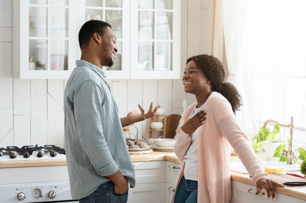 black couple laughing and chatting in kitchen