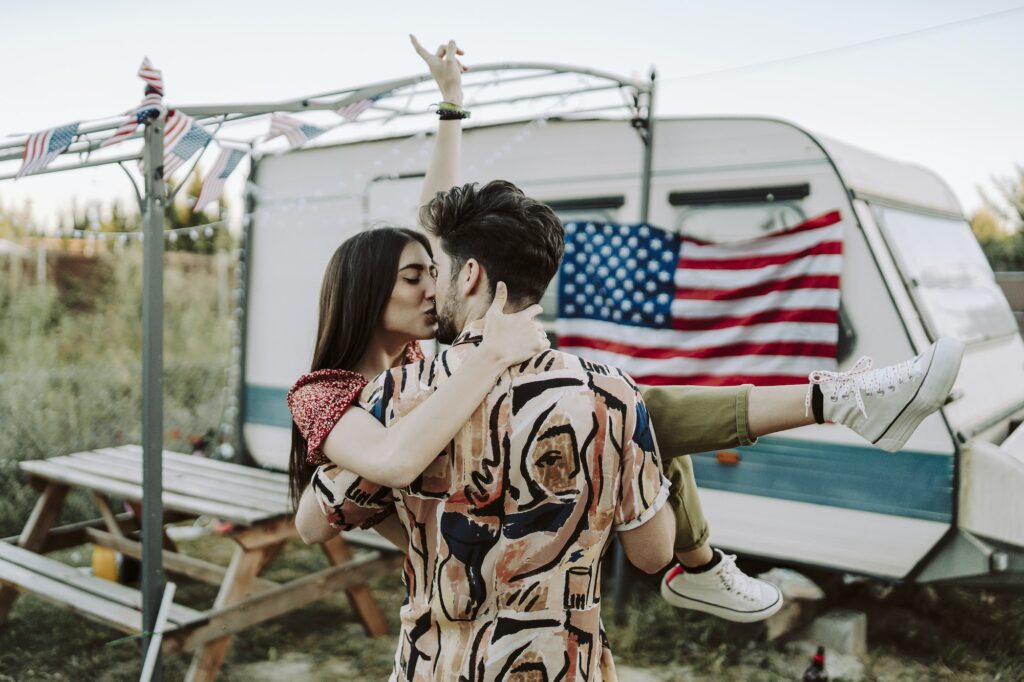 Beautiful Spanish couple kissing on background of the US flag - US Independence day