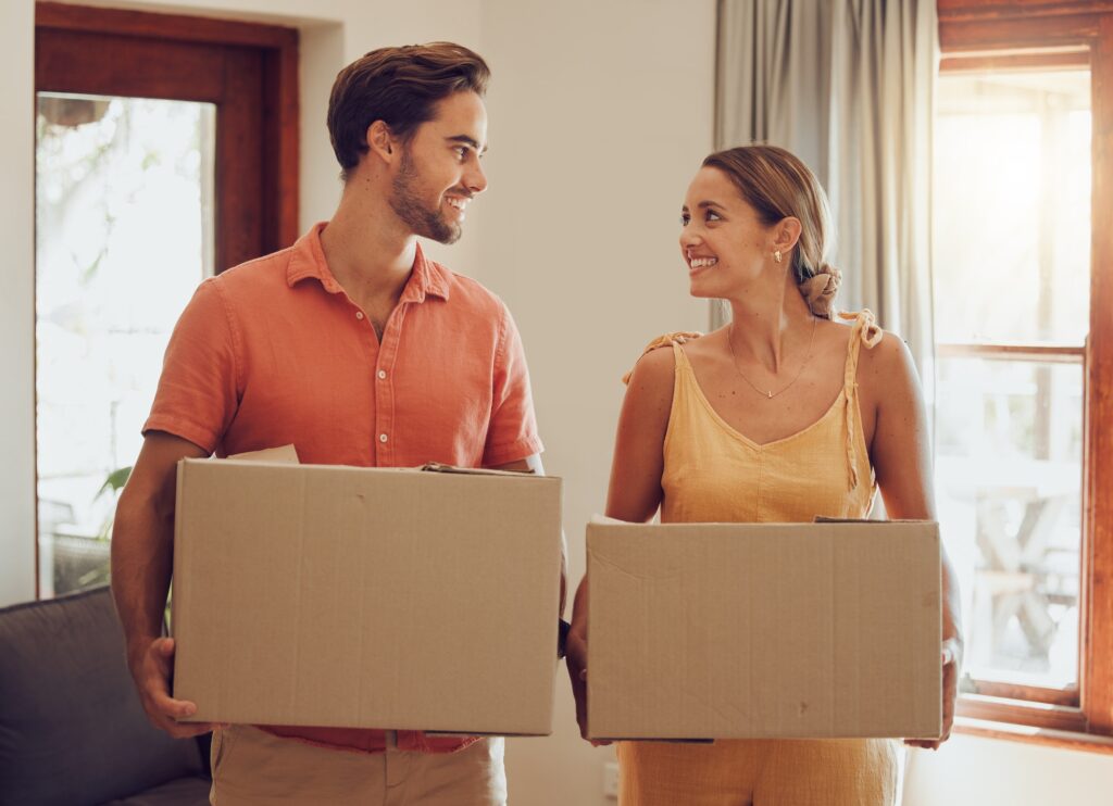 moving home and couple holding boxes while looking happy